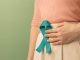 Ovarian and Cervical Cancer Awareness. Woman Holding Teal Ribbon on Lower Abdomen, Uterus, Female Reproductive System, Women's Health, PCOS and Gynecology