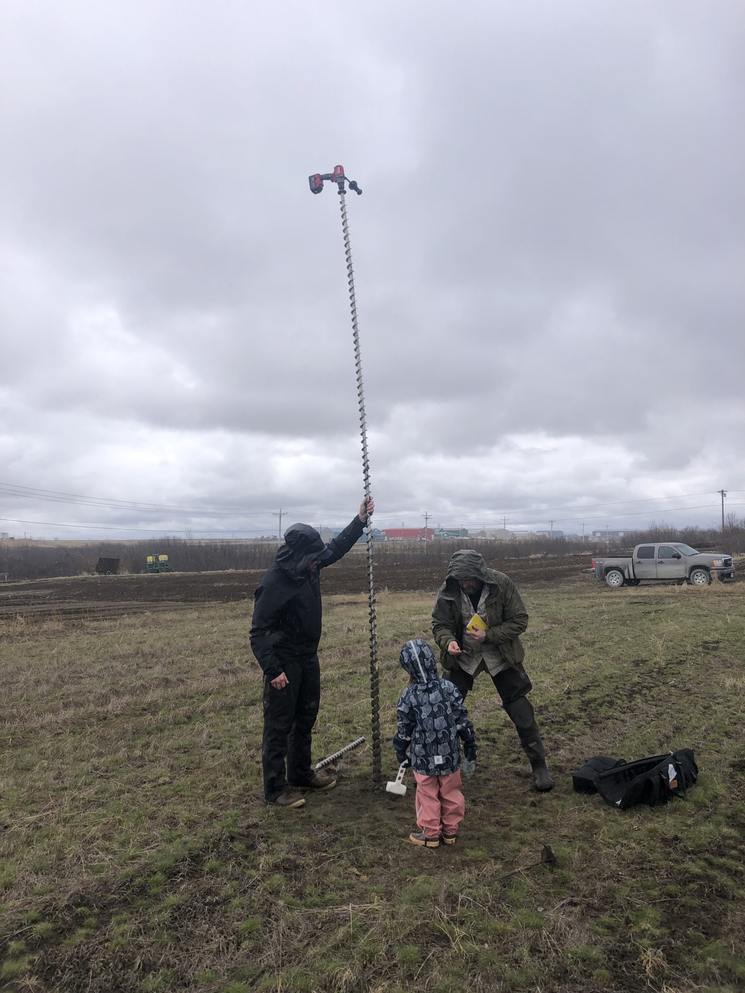 Figure 2: Permafrost Grown team members drill to the permafrost table at a farm in Bethel, AK, using an electric drill with an auger attachment. The image shows ~4 m of auger flights pulled from the ground after permafrost was found.