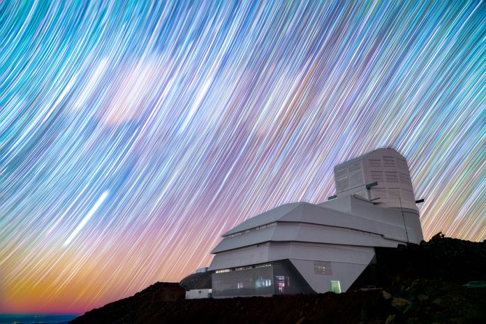 Rubin Observatory stands on Cerro Pachón in Chile against a sky full of star trails in this long exposure night sky image.