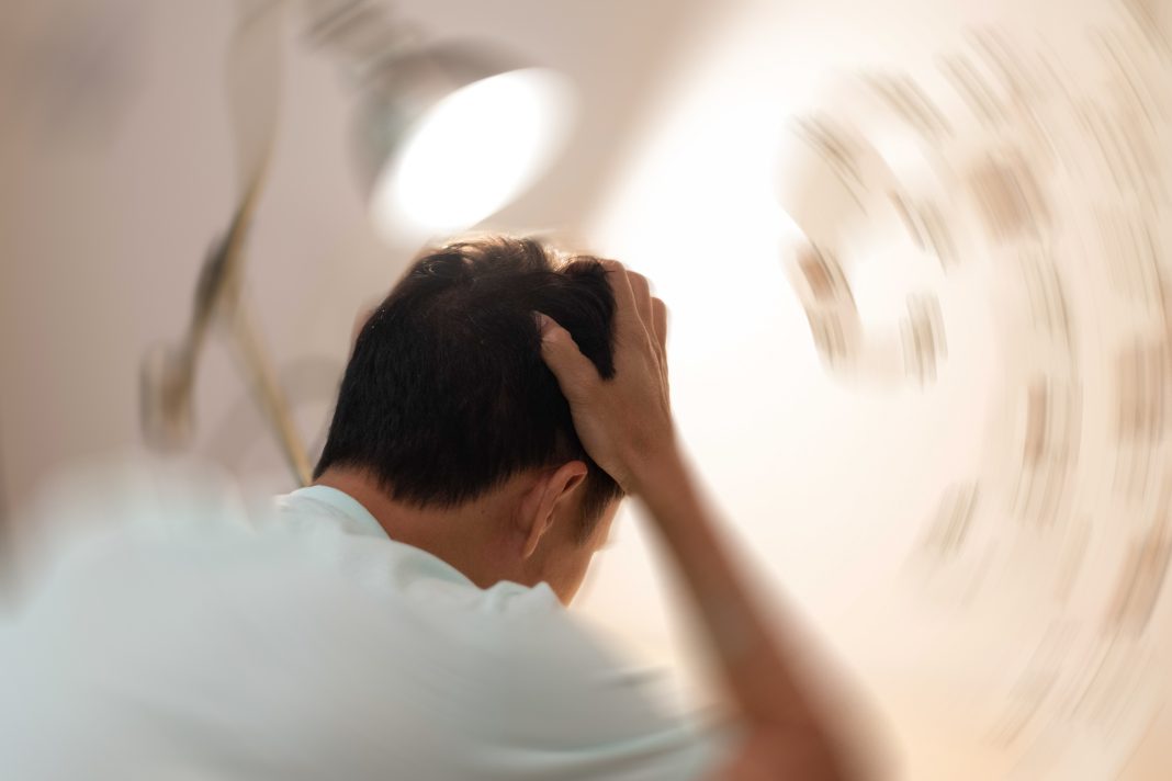 Vertigo illness concept. Man hands on his head felling headache dizzy sense of spinning dizziness,a problem with the inner ear, brain, or sensory nerve pathway.