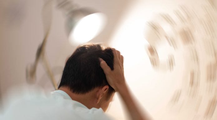 Vertigo illness concept. Man hands on his head felling headache dizzy sense of spinning dizziness,a problem with the inner ear, brain, or sensory nerve pathway.