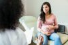 Expectant mother touches abdomen while listening to unrecognizable doctor