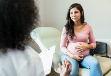 Expectant mother touches abdomen while listening to unrecognizable doctor