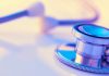 Close-up of a stethoscope on a desk. Shallow depth of field, space for copy. Toned image.