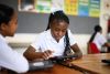 Schoolgirl sitting at group desk working on digital tablet