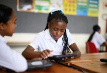 Schoolgirl sitting at group desk working on digital tablet