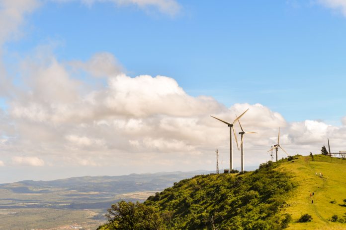 Scenic View Of Landscape And Wind Turbines Against Sky