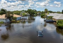 Hurricane rainfall flooded road. Drowned car on city street in Florida residential area. Consequences of hurricane natural disaster.