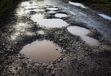 A wet rural road with bad potholes.