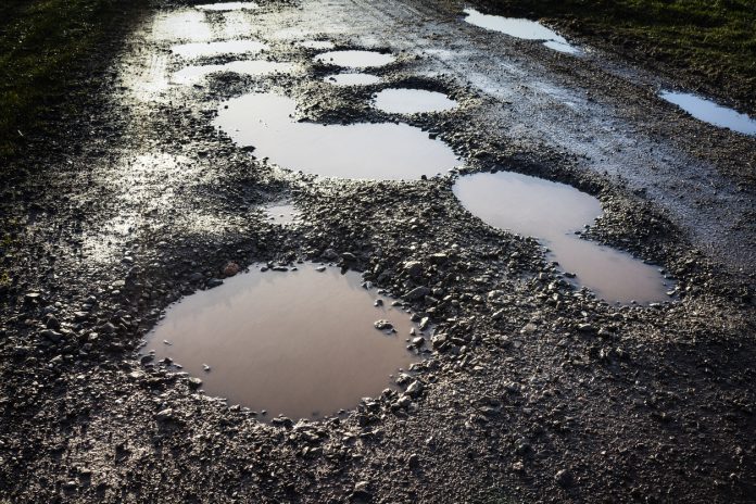 A wet rural road with bad potholes.