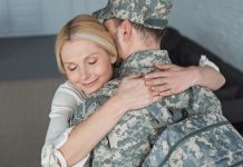 smiling mother hugging grown son in military uniform at home