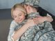 smiling mother hugging grown son in military uniform at home