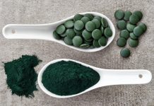 Spirulina algae powder and tablets on gray background from top view