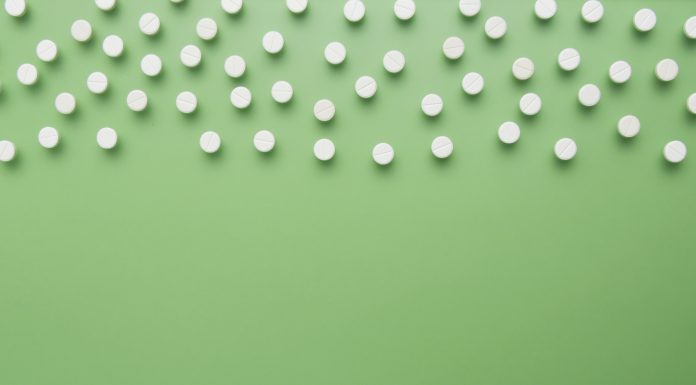 White pills on green background isolated. Flat lay. Copy space.