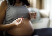 Pregnant woman taking pill at home