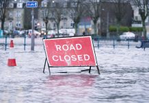 Road flood closed sign under deep water during bad extreme heavy rain storm weather in UK