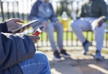 Close Up Of Teenagers With Mobile Phone Vaping and Drinking Alcohol In Park