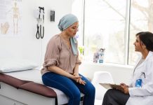 Female cancer patient shares symptoms with cheerful female doctor