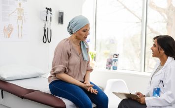 Female cancer patient shares symptoms with cheerful female doctor