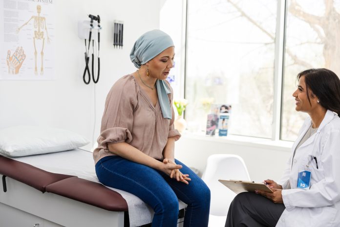 Female cancer patient shares symptoms with cheerful female doctor