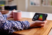 Close Up Of Woman Holding Smart Energy Meter In Kitchen Measuring Energy Efficiency