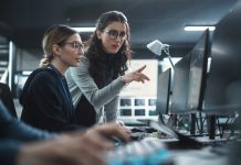 Two Beautiful Women Working in a Cyber Security Software Development Department. Young Manager Updating Software Developer on the Artificial Intelligence Safety Project