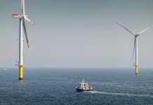 Epic Sunrise over Offshore Wind farm and substation on the horizont, vessel between them, bright sky, Borkum Riffgrund Germany