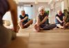 Group of mature people doing stretching exercises with their coach during a Yoga class in a studio. Focus is on senior woman. Copy space.