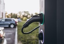 Electric car charging at plug in charging station in a public car park.