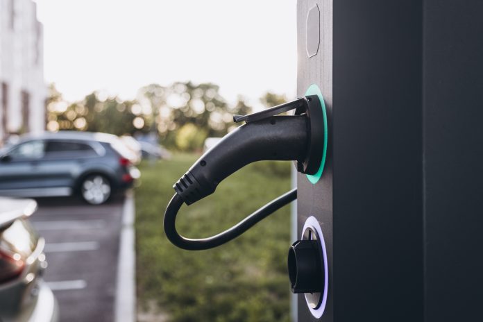 Electric car charging at plug in charging station in a public car park.