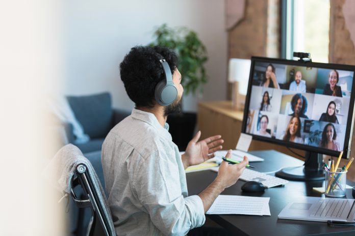 Man in Headphones Participating in a Virtual Group Meeting