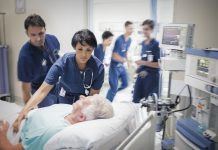 Two doctors preparing elderly patient before medical procedure